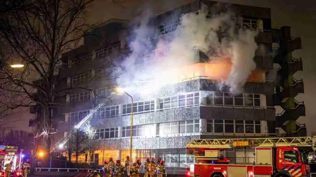 Brandweer bestrijdt uitslaande brand in flatgebouw tijdens de nacht, met rookontwikkeling en inzet van hoogwerker.