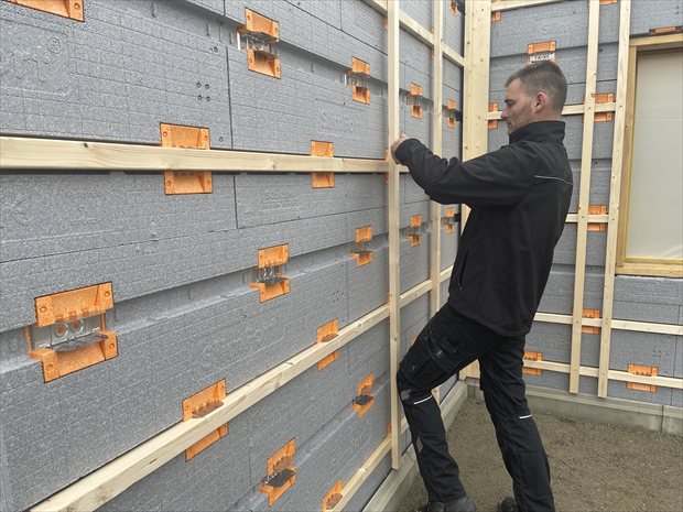 Montage van een droog gevelsysteem met geïntegreerde isolatieplaten en bevestigingsbeugels.
