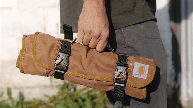 Gereedschap roltas wordt compact opgerold gedragen door vakman op locatie.