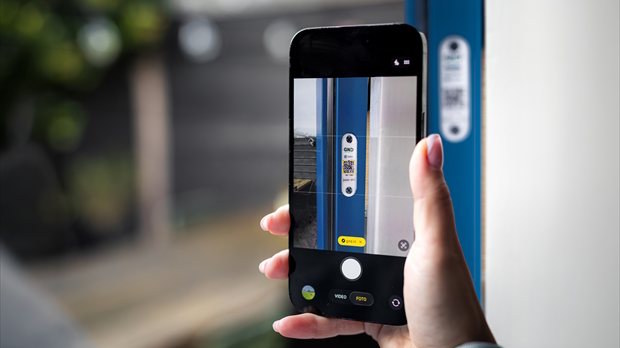 Smartphone scant QR-code op GND deurlabel in kozijn