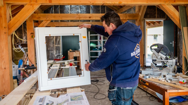 Vakman van Bouwbedrijf Bolderbouw monteert kozijn in werkplaats
