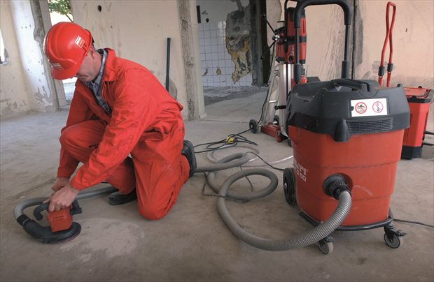 Werknemer schuurt vloer met stofafzuiging om kwartsstof te beperken | BouwTotaal Werknemer schuurt vloer met stofafzuiging om kwartsstof te beperken