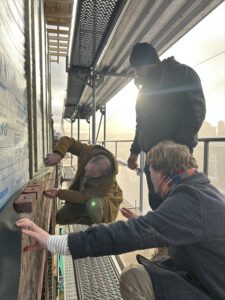 Vakmensen op steiger bespreken geveldetail tijdens samenwerking in de bouw