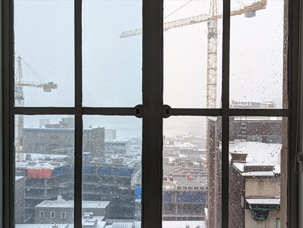 Uitzicht door raam met Nano-raamfolie GlassShield tijdens winterse omstandigheden in stedelijk gebied | BouwTotaal Uitzicht door raam met Nano-raamfolie GlassShield tijdens winterse omstandigheden in stedelijk gebied