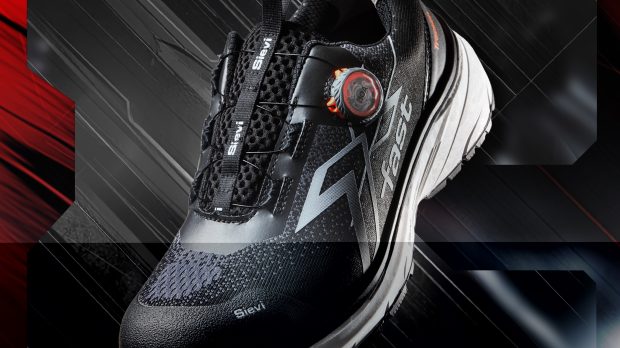 Close-up of a black athletic running shoe with orange accents against a red/gray abstract background.