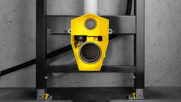 Yellow safety interlock mounted on a black metal frame with a circular sensor in a workshop setting.
